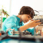 Enthusiastic pupil fixing the robot at science lesson